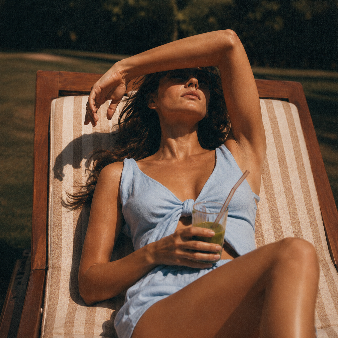 Frau im hellblauen Badeanzug mit grünem Drink in der Sonne als Symbol für Darmgesundheit und Functional Beauty.